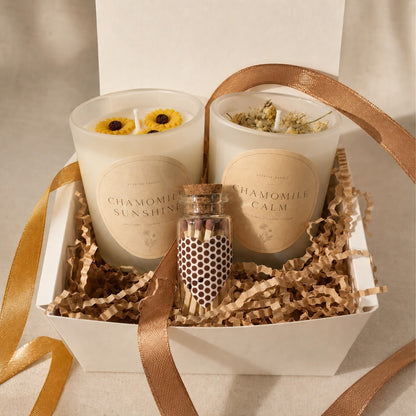 Two handmade camomile candles in a gift box with a small bottle of matches