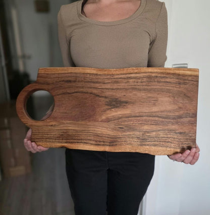 Large acacia wood chopping block held to show its generous approximately 57 by 26 cm size