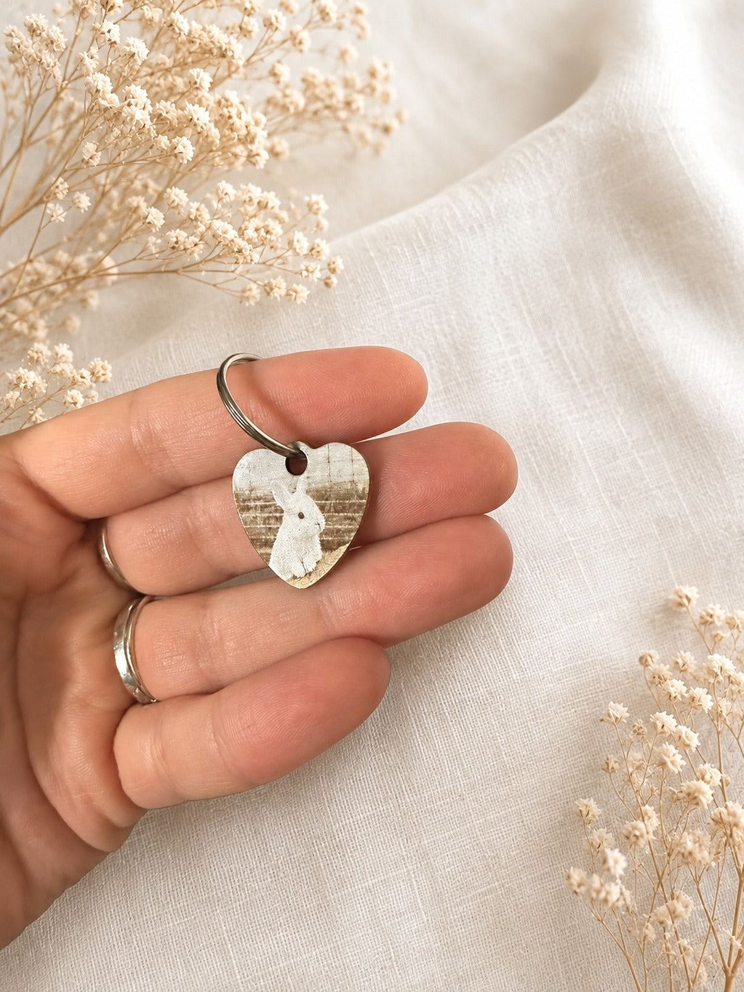 Personalised pet photo keyring held in hand, featuring a heart shape with a pet image and floral background.