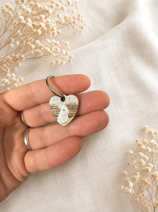 Personalised pet photo keyring held in hand, featuring a heart shape with a pet image and floral background.