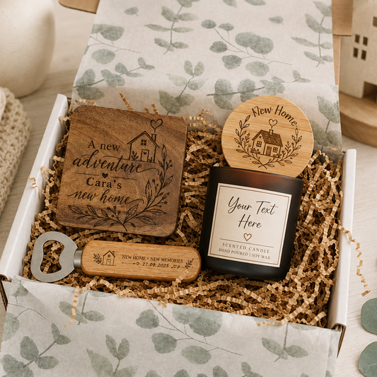 A curated gift box set containing personalized wooden home decor and a candle. The set includes a square wooden plaque engraved with 'A new adventure Cara's new home', a round wooden lid with a house engraving, a black glass candle jar with a white label reading 'Your Text Here', and a wooden bottle opener engraved 